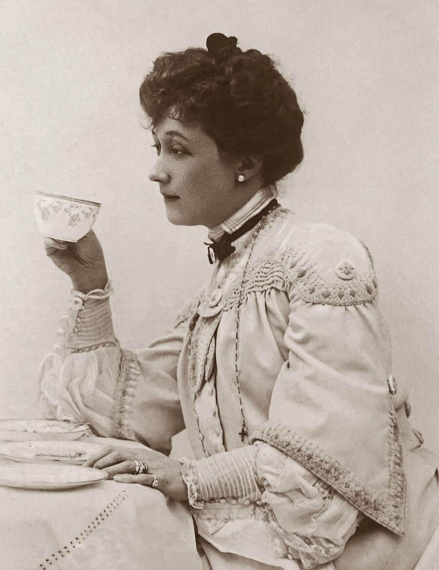 Dame prenant le café – Belle Époque Femme de la Belle Époque assise à une table, portant une tasse à ses lèvres.